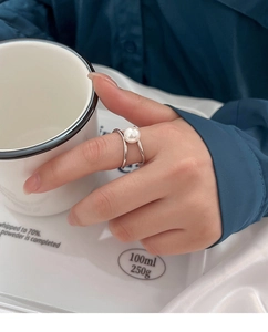 Close-up of minimalist silver open ring with a round white pearl on a elegant background