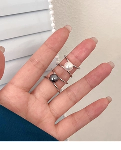 Close-up of elegant white and grey pearl rings with minimalist silver cross band design