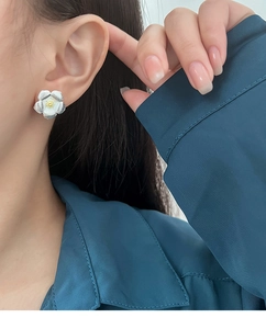 Gros plan de boucles d'oreilles minimalistes en argent en forme de gardénia