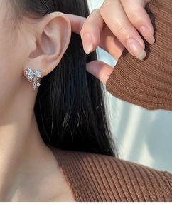 Macro view of bow knot earrings with tassels and star pendants featuring shiny zircon