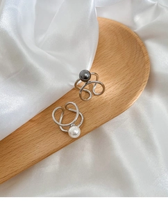 Detail of adjustable silver-plated ring with black and white pearls on white silk