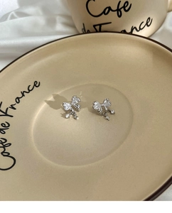 Detail of silver bow earrings with sparkling cubic zirconia and star pendant charms