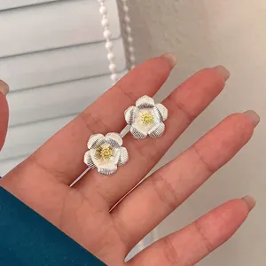 Boucles d'oreilles gardénia avec pétales ondulés et pistil jaune tenues à la main