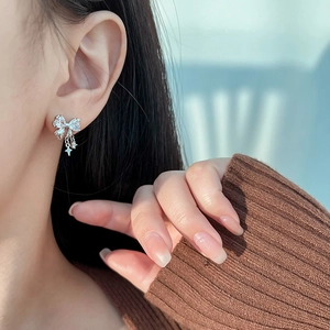 Sparkling silver bow knot earrings with star tassels on model in a cozy sweater