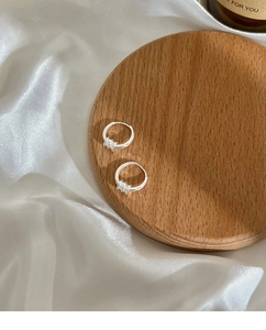 Detailweergave van zilveren oorringen op hout en zijde met elegante verlichtingstijl