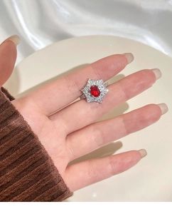Makroaufnahme einer Frau mit Taubenblut-Rubinring und funkelndem Diamant-Halo-Effekt