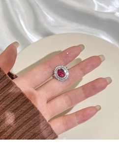 Detail view of Lady Di style halo ring with oval red gemstone and white crystals