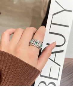 Close-up of emerald green square stones on hollow chain link open ring on hand