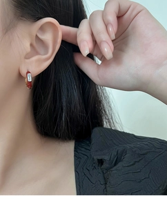 Detalle de pendientes de aro en esmalte rojo con circón transparente en la modelo