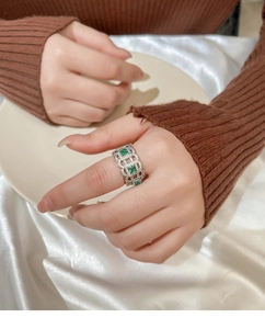 Detail of silver lace hollow ring with emerald green stones and pavé set cubic zirconia