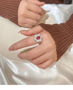Makroaufnahme eines Rubinrings mit ovalem Stein und Diamant-Halo im Stern-Design