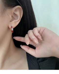 Detalle de pendiente de aro en esmalte rojo con circón de corte baguette en oro