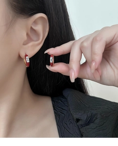 Detalle de pendientes de aro en esmalte rojo con circón baguette y acabado dorado