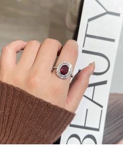 Detailed view of an oval red gemstone ring with double-layered white zircon halo setting
