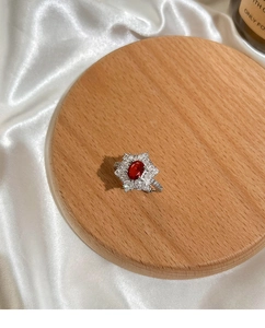 Detailansicht eines taubenblutroten Edelsteinrings mit floralem Diamant-Halo-Design