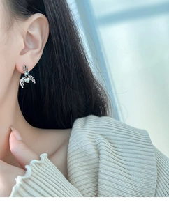 Detail of vintage silver crown earrings with blue gemstone and bat wings on model