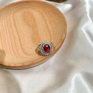 Retro silver ring featuring oval red gemstone with double white zircon halo on silk fabric