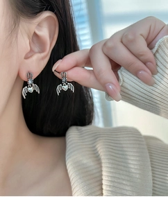 Close-up of crown heart devil wing earrings in vintage silver on a female model