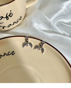 Macro detail of gothic crown and bat wing earrings with heart on vintage plate