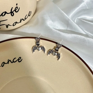 Gothic crown heart devil wing earrings in vintage silver finish on ceramic tray