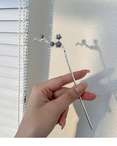 Close-up of a silver plum blossom hair stick featuring detailed floral metal textures