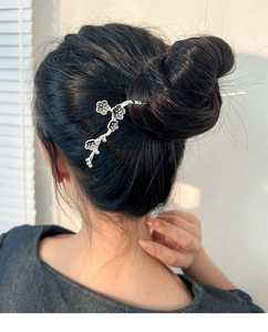 Close-up of silver plum blossom hair stick styled in a traditional bun with soft natural lighting
