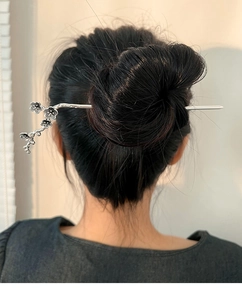 Detailed view of silver plum blossom hair stick in a classic bun hairstyle