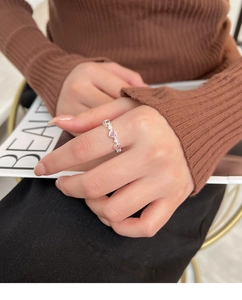 Detail of a silver ring featuring three pink heart-shaped stones and tiny white diamonds