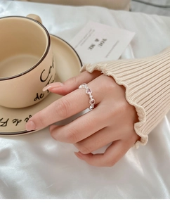 Detail showing pink heart-shaped crystal ring worn on finger with soft background
