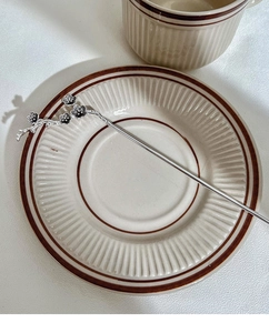Close-up of a silver plum blossom hair pin on a ceramic plate with oriental aesthetics