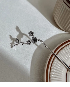 Detail of silver plum blossom hair pin with intricate floral textures and elegant shadows