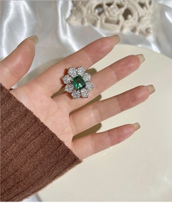 Détail de la bague de luxe avec pierre verte et pétales de fleurs sertis de diamants