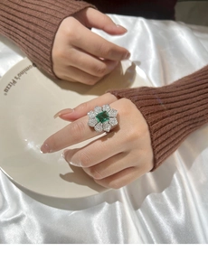 Vue détaillée d'une bague fleur de luxe vert émeraude avec métal argenté et pierres zircons