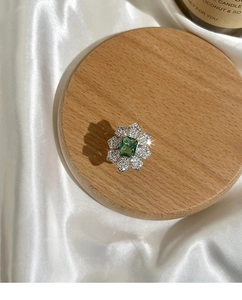 Détail d'une bague fleur avec pierre verte coupe émeraude et pétales en cristal