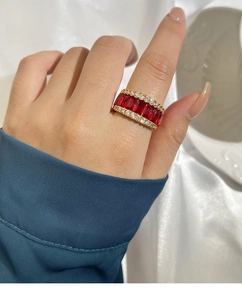 Détail d'une bague vintage en or avec rubis rouges sertis et bordures en diamants blancs