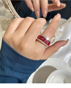 Gros plan d'une bague de luxe en or avec pierres rouges portée au doigt d'une femme