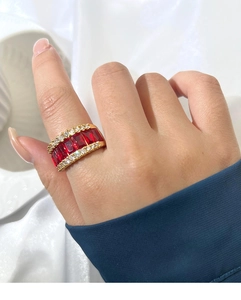 Macro d'une bague dorée ornée de cinq pierres rouges baguette et de cristaux étincelants
