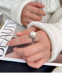 Makroaufnahme von Retro-Ring mit hohlem Silbermuster und einer großen weißen Perle