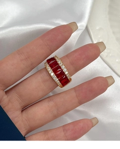 Gros plan d'une bague dorée avec quatre pierres rouges et rangées de zircons blancs