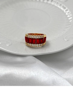 Vue macro d'une bague dorée avec pierres rouges rectangulaires et brillants sur satin