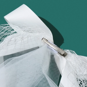 Detail of white satin bow hair clip with sheer mesh veil and silver alligator clip