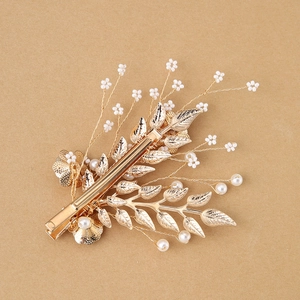 Close-up of golden leaf hair clip with white small pearls and forest-style design