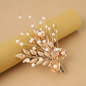 Detailed macro view of golden leaf and pearl hair clip showing craftsmanship and wire wrapping