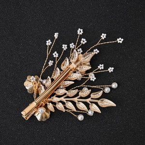 Elegant gold leaf hair clip with white pearl floral accents on black background