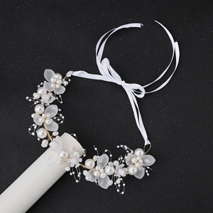 Détail de bandeau de mariée avec fleurs givrées, perles et fil doré sur fond sombre