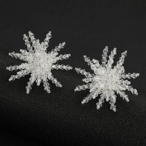 Handmade crystal snowflake tassel earrings with radiant faceted beads on a black stand