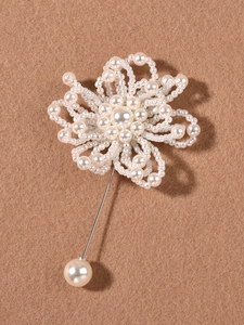 Detalle de un broche de boda artesanal con flores de perlas blancas y alfiler de plata
