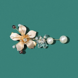 Barrette à fleurs dorée élégante avec perles et cristaux sur un fond vert foncé