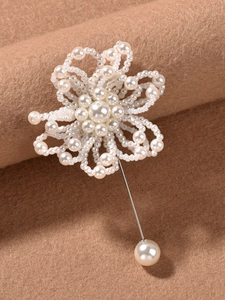 Primer plano de un prendedor de flores de perlas hechas a mano sobre lana de camello