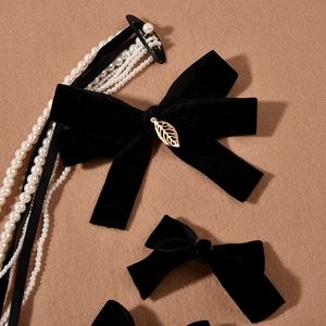 Detail of black velvet bow hair accessory with gold leaves and pearl tassels